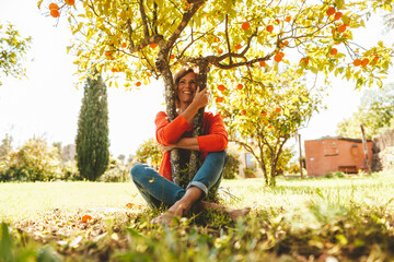 Cheerful mature woman hugging orange fruit tree