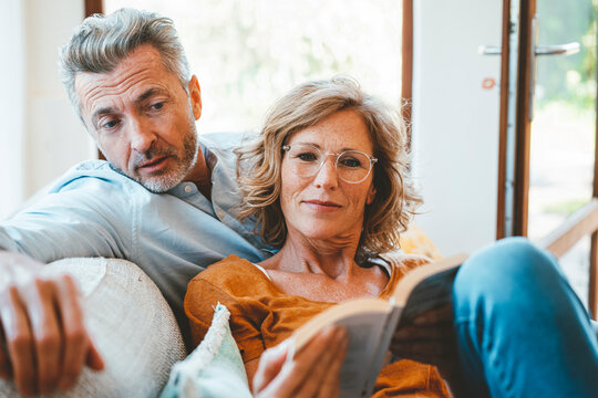 Mature Woman And Man Reading Book Together At Home