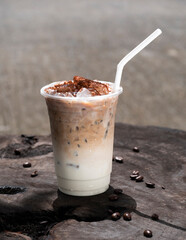 Cappuccino iced coffee with coffee beans on the wooden table.