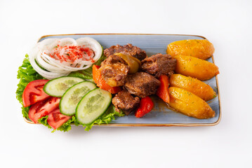 stewed meat with potatoes and fresh tomatoes, cucumbers and onions on a white background