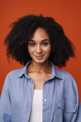 Young middle-eastern woman with curly hair smiling at camera