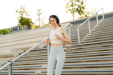 Young sportswoman using headphones doing workout on stairs outdoors