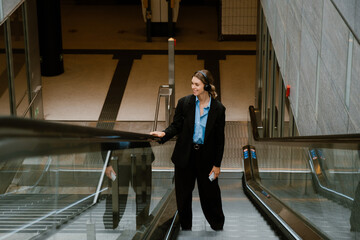 Young woman in headphones while standing on the escalator