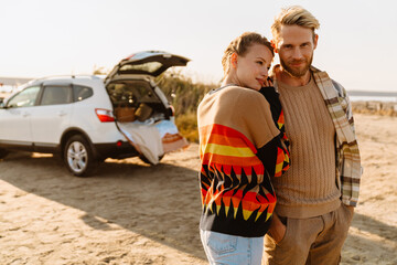 Fototapeta premium Happy young white couple smiling and hugging while walking by seashore