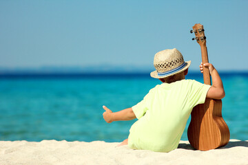 child with guitar by the sea