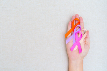 World cancer day, February 4. Hand holding orange, pink, peach and purple ribbons for supporting...