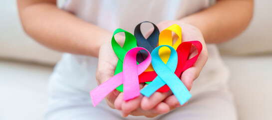 World cancer day, February 4. Hand holding blue, red, green, pink, black and yellow ribbons for...