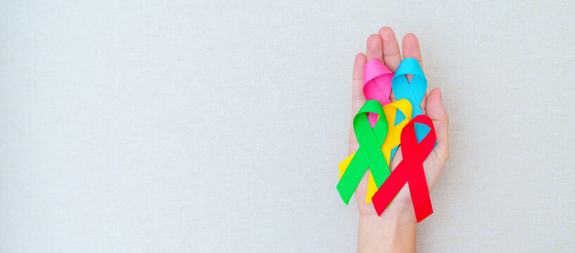 World cancer day, February 4. Hand holding blue, red, green, pink and yellow ribbons for supporting people living and illness. Healthcare and Autism awareness day concept