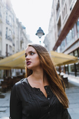 Young adult woman looking away from camera standing outside in a city center.