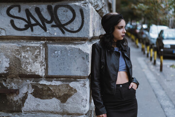 Portrait of a young woman wearing all black lying on a brick wall