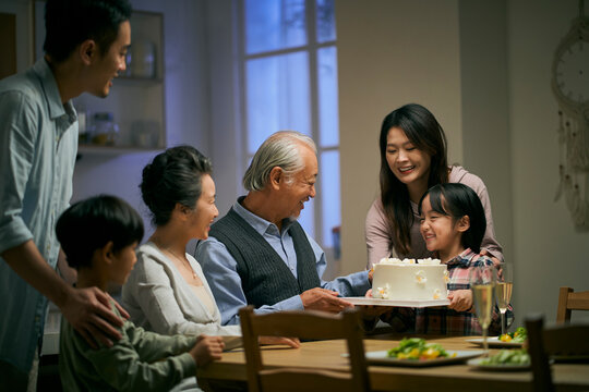 senior asian couple celebrating wedding annversary with three generational family