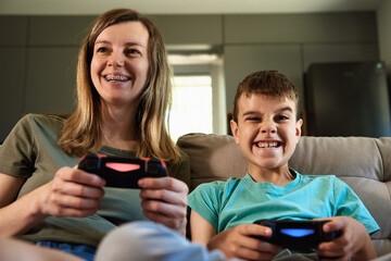 Son and mother playing video game at home, Family spending time together, Happy relationship,...
