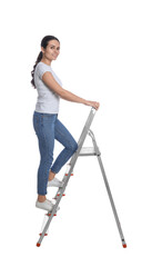 Young woman climbing up metal ladder on white background © New Africa