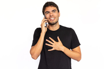 Happy young man talking on phone. Cheerful Caucasian male model with short dark hair in black T-shirt looking away with hand on chest, calling ad number. Modern technology, advertising concept