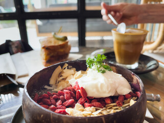 Yogurt, red goji berries and dried fruits bowl with coffee glass at cafe table