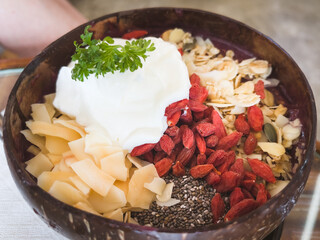 Goji berries, dried fruits and yogurt on coconut bowl. Healthy breakfast concept