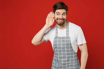 Young curious nosy fun male housewife housekeeper chef cook baker man wear grey apron try to hear...