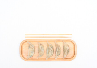 Delicious asian dumplings on wooden plate with chopsticks on white background. Selective focus. Asian food concept