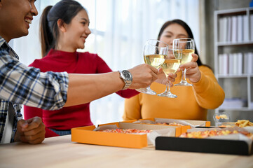 Group of Asian friends having party at home, drinking, toasting and clinking glasses with wine