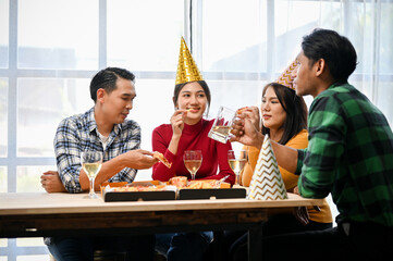Group of happy and joyful Asian friends enjoy talking while drinking beer and eating pizza together