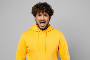 Fototapeta na wymiar Young indignant dissatisfied furious displeased sad mad Indian man 20s he wearing casual yellow hoody look camera scream isolated on plain grey background studio portrait. People lifestyle portrait.