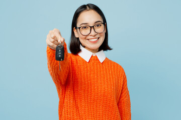 Young happy smiling fun woman of Asian ethnicity wear orange sweater glasses hold give car keys fob...