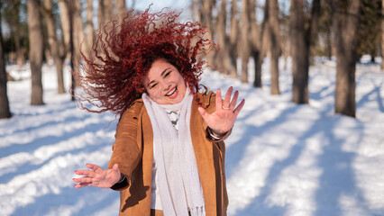 Fat caucasian woman dancing on a walk in the park in winter. 