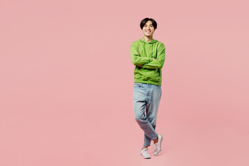 Full body smiling happy fun young man of Asian ethnicity wear green hoody look camera hold hands...