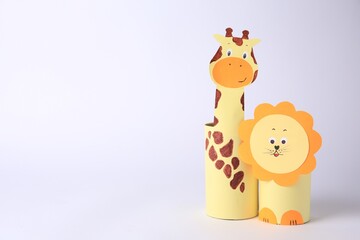 Toy giraffe and lion made from toilet paper hubs on white background, space for text. Children's handmade ideas