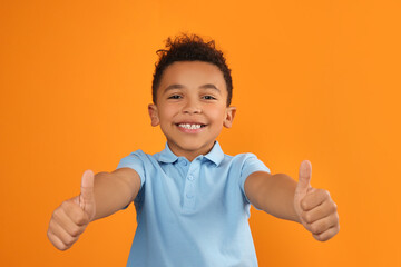 African-American boy showing thumbs up on orange background