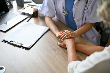 A professional female doctor holding her patient's hands on the table