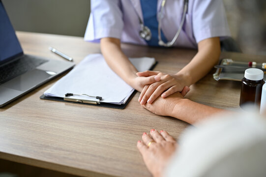 close-up image, A female doctor holds a patient's hand to comfort and reassure the patient