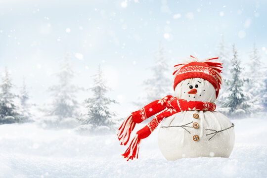 happy snowman in a snowdrift, in a red hat and scarf against the backdrop of a winter forest