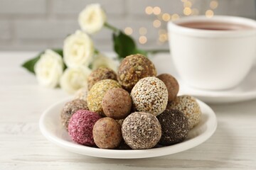 Delicious vegan candy balls on white wooden table against blurred lights