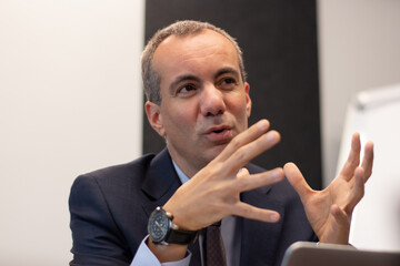 Portrait of businessman talking to team in office. Serious man in formalwear working discussing projects with colleagues and explaining his position on business growth. Business growth concept