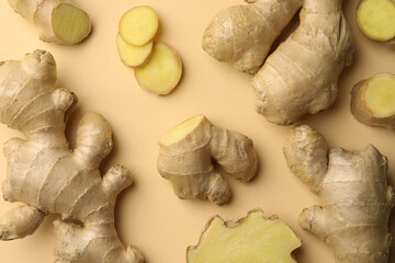 Fresh ginger with green leaves on beige background, flat lay
