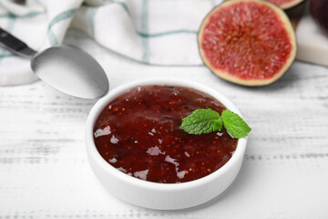 Tasty sweet fig jam and fruits on white wooden table, closeup