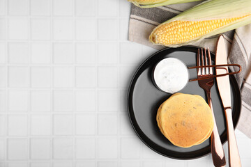 Tasty corn pancakes with sauce served on white tiled table, flat lay. Space for text