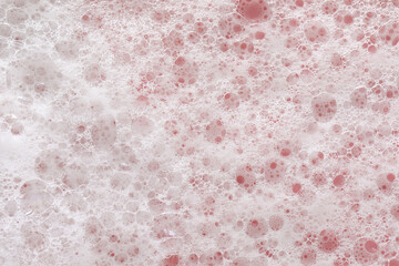 White washing foam on pale pink background, top view