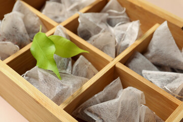 Fototapeta na wymiar Many tea bags in wooden box and leaves, closeup