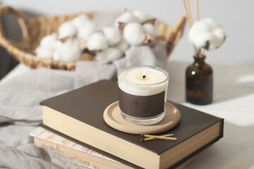 hygge concept. cozy ambient home interior decor with candle, cotton buds and aroma diffuser. burning coconut wax candle