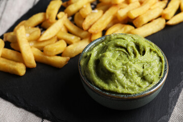 French fries and avocado dip on serving board, closeup