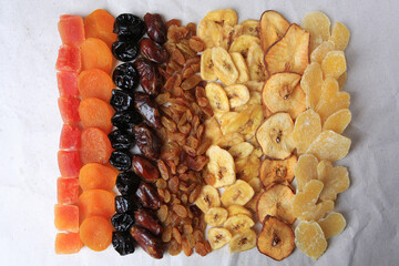 Different tasty dried fruits on paper, flat lay