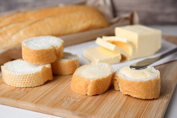 Fototapeta na wymiar Tasty cut baguette with fresh butter on white table, closeup