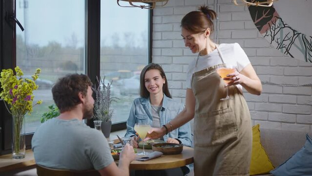 A friendly waitress in a cozy cafe brought drinks to a pleasant couple. A man and a woman came to lunch at a health food restaurant.