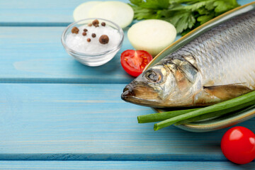 Delicious salted herring and ingredients on light blue wooden table, closeup. Space for text