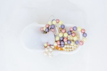 White bathtub full of colorful beads and foam decorations. Top view. Copy space