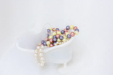 White bubble bath full of colorful beads and pearls. Copy space. Isolated