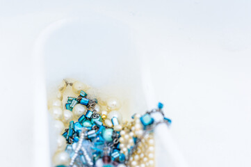 White bathtub with foam and blue and white beads. Close up. Copy space. Top view