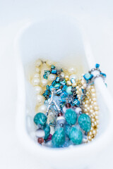 White bubble bath filled with blue stones and white pearls. Top view